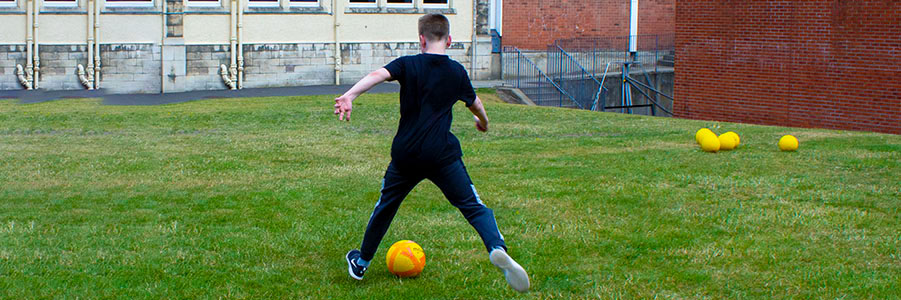 A young person kicking a ball at the Positive Transitions summer programmeq