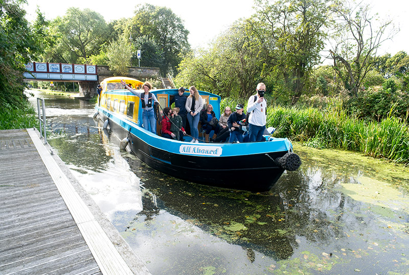 A group of people on the All Aboard canal boat as it sails down the Union Canal