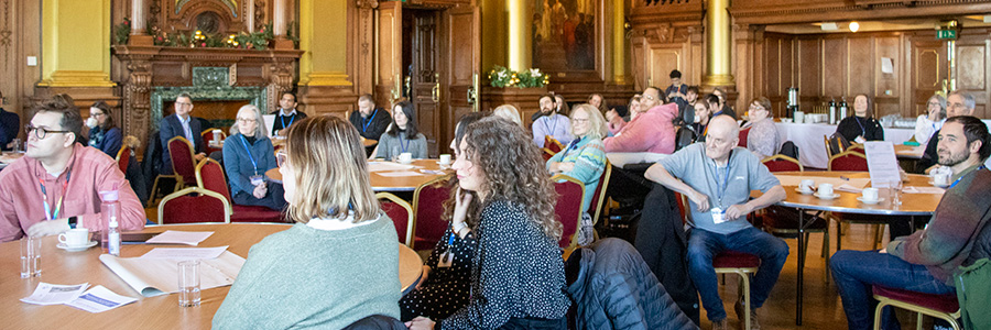 People sitting at tables during an event on digital inclusion in the Edinburgh City Chambers