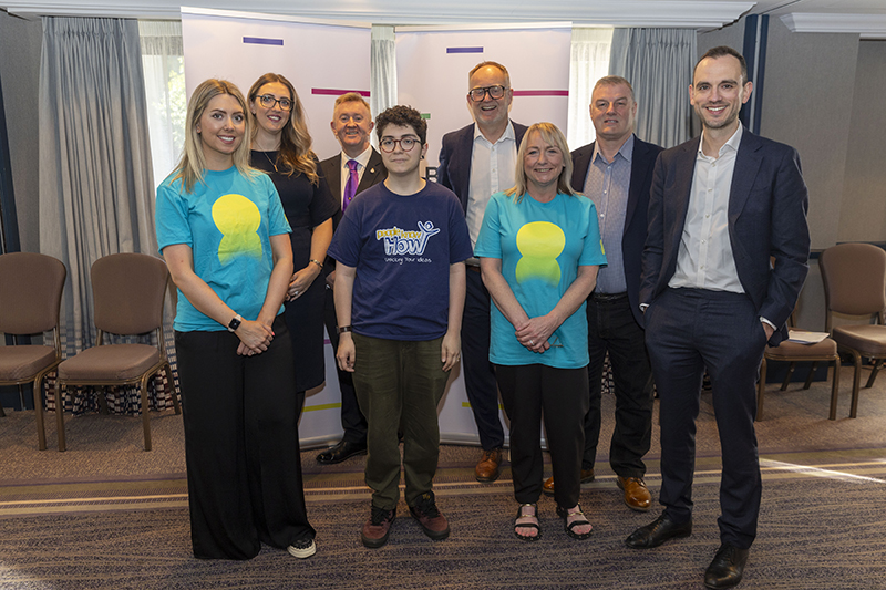 A group of people from BT and People Know How standing in front of banners